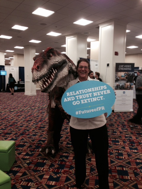 Gina Milani at a PR event holding a #FutureofPR sign that reads: Relationships and trust never go extinct